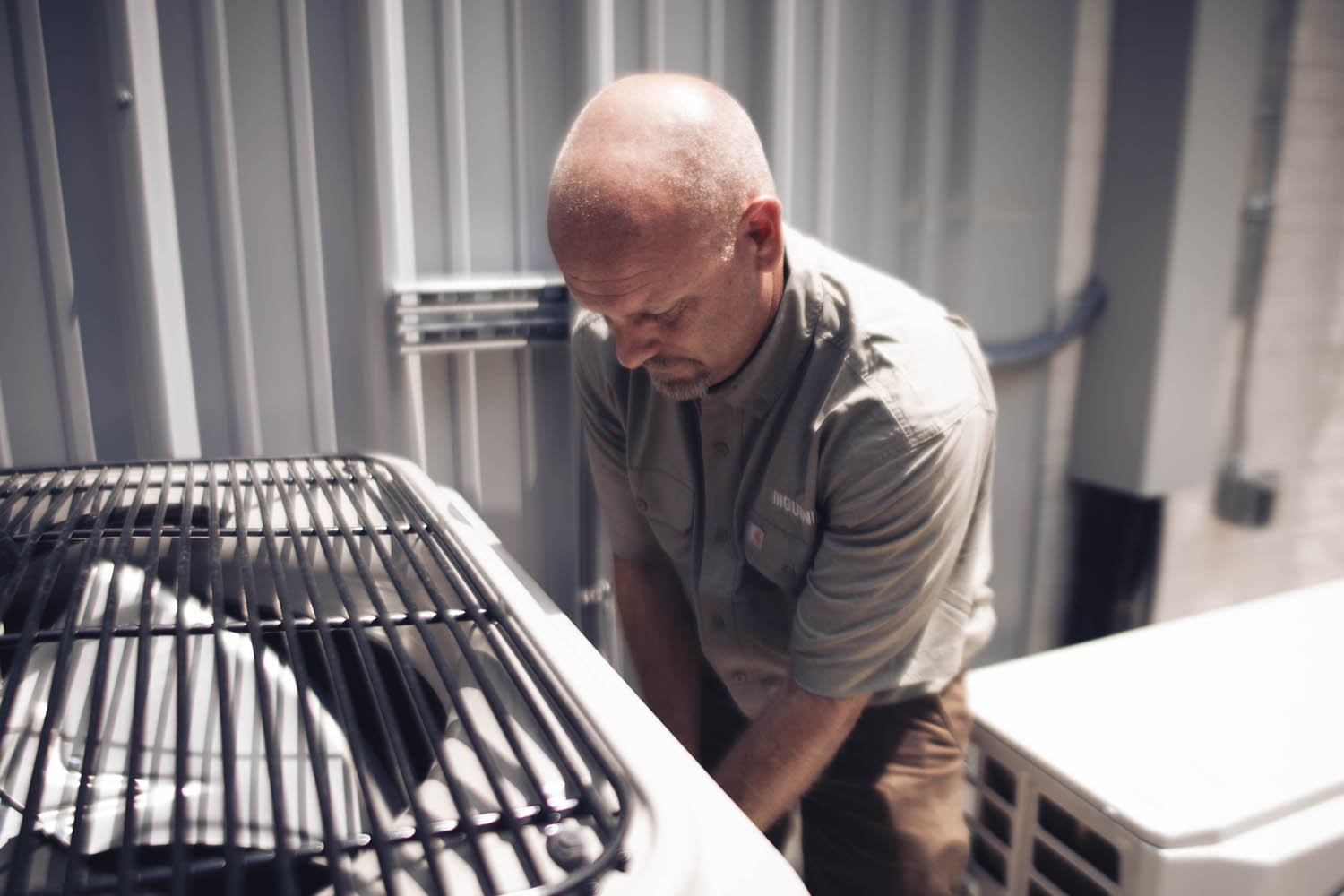A person working on an outdoor air conditioning unit.